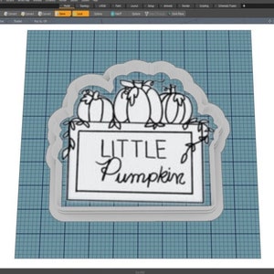 May include: A white cookie cutter in the shape of a sign with three pumpkins on top. The sign says "LITTLE Pumpkin".
