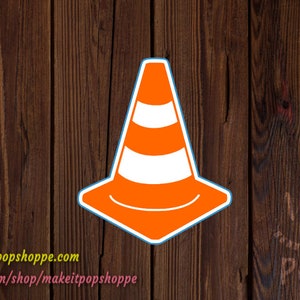 May include: Orange and white traffic cone sticker with a blue outline. The sticker is on a brown wooden background.