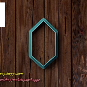 May include: A teal blue plastic cookie cutter shaped like a hexagon. The cookie cutter is on a brown wooden background.