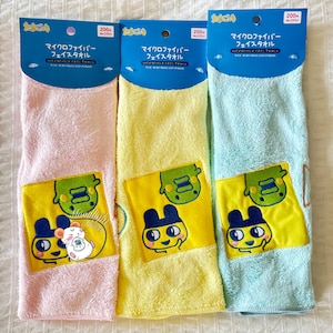 Puede incluir: Tres toallas faciales de microfibra en rosa, amarillo y azul. Cada toalla tiene un parche amarillo con un diseño de personaje de dibujos animados. Las toallas están empaquetadas con un encabezado azul que incluye texto japonés.
