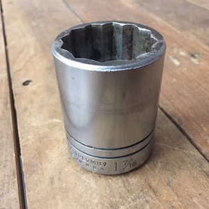May include: A silver socket wrench with a 1 7/16 inch size marking. The socket is made in the USA.