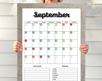 May include: A white dry-erase calendar with a gray frame. The calendar is for September and has a rainbow color scheme. The days of the week are listed at the top, and the numbers 1 through 30 are listed in a grid. There are also sections for notes and a menu.