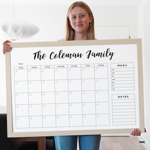 May include: A white dry-erase board with a wooden frame. The board has a monthly calendar, a menu section, and a notes section. The text "The Coleman Family" is written at the top of the board.