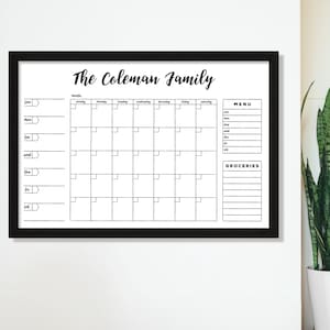 May include: A black framed dry erase board with a white background. The board is divided into sections for a monthly calendar, a menu, and a grocery list. The title at the top reads "The Coleman Family".