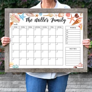 May include: A white dry-erase calendar with a seashell theme. The calendar has a monthly view with spaces for each day of the week. The top of the calendar says "The Miller Family". There is a menu and notes section on the right side of the calendar.