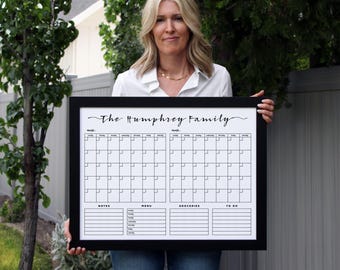 May include: A black framed dry-erase calendar with the text "The Humphrey Family" at the top. The calendar has two monthly calendars, a notes section, a menu section, a groceries section, and a to-do list section.