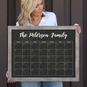 Puede incluir: Una pizarra enmarcada en gris con el texto "The Peterson Family" en la parte superior. La pizarra tiene una cuadrícula de cuadrados para cada día de la semana, con los días de la semana etiquetados en la parte superior.