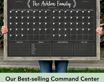 May include: A black chalkboard with a wood frame and a white calendar grid. The calendar is divided into two sections, each with a month's worth of days. The top of the board has the text "The Ashton Family Established 2018" and a decorative wreath. Below the calendar are sections for notes, menu, groceries, and to do.