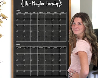 May include: A black chalkboard with a wooden frame and the text "The Naylor Family" in white cursive lettering. The chalkboard is divided into two sections, each with a monthly calendar grid. The calendar grid has the days of the week labeled at the top and the numbers of the month in each square.