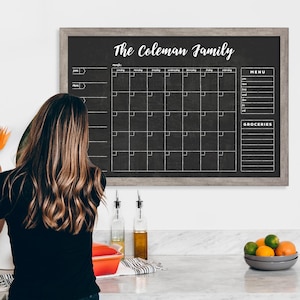 May include: A black chalkboard with a gray wood frame, labeled "The Coleman Family". The chalkboard has a monthly calendar grid, a menu section, and a grocery list section.