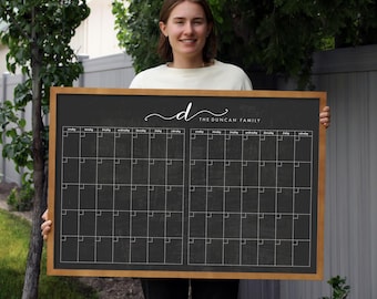 May include: A black chalkboard with a wooden frame, divided into two monthly calendars. The top of the board has the text "The Duncan Family" in white cursive writing.