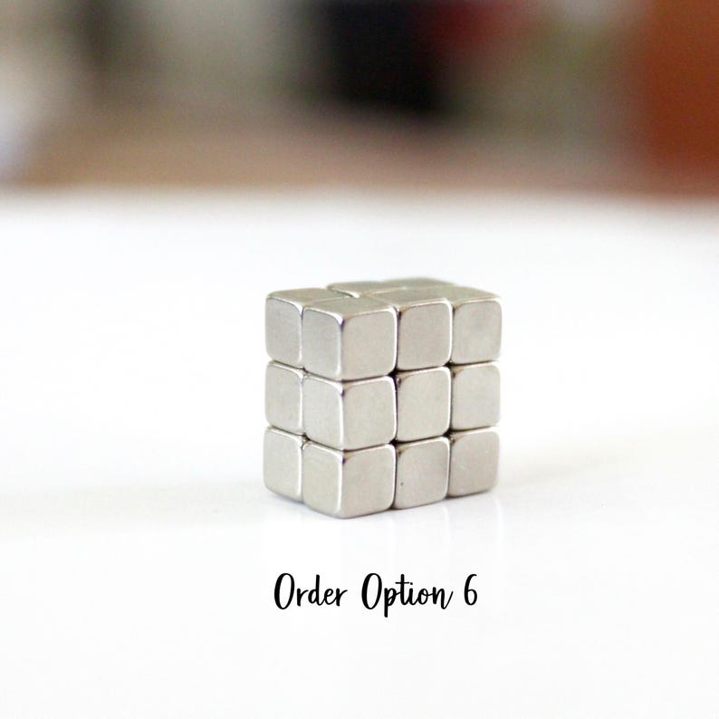 May include: A silver cube made of smaller, square blocks. The cube is centered on a white surface. The text "Order Option 6" is written in black cursive font below the cube.