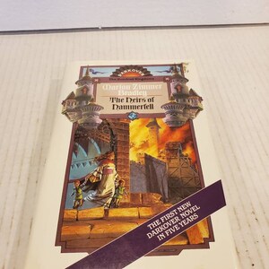 May include: A book cover featuring a fantasy illustration of a burning city with a woman and two children on a wall. The title is "The Heirs of Dammerfell" by Darion Zimmer Bradley. The subtitle is "The Hundred Kingdoms". The text "The First New Darkover Novel in Five Years" is on a purple banner.