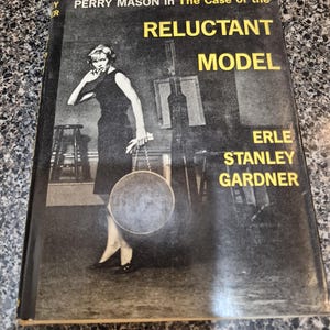 May include: Vintage paperback book titled "PERRY MASON in The Case of the RELUCTANT MODEL" by Erle Stanley Gardner. The cover features a black and white image of a woman in a dress holding a circular object.