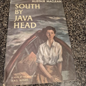 Peut inclure: Livre de poche vintage intitulé "South by Java Head" d'Alistair MacLean. La couverture présente une femme dans un bateau avec une mer agitée en arrière-plan. Le livre est un roman de l'auteur de "H.M.S. Ulysses".