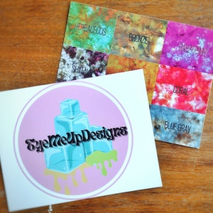 May include: Two cards on a wooden surface. One card features a logo with the text "EyeMeUpDesigns" and a design of blue ice cubes with green and yellow drips. The other card displays color swatches labeled "Herbaceous", "Bronze", "Raspberry", "Shitai", "Coral", and "Blue Gray".