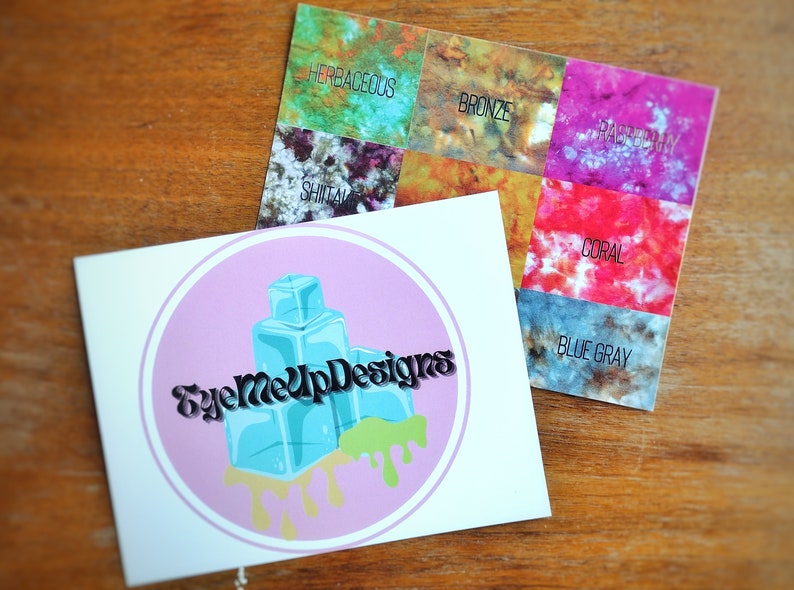 May include: Two cards on a wooden surface. One card features a logo with the text "EyeMeUpDesigns" and a design of blue ice cubes with green and yellow drips. The other card displays color swatches labeled "Herbaceous", "Bronze", "Raspberry", "Shitai", "Coral", and "Blue Gray".