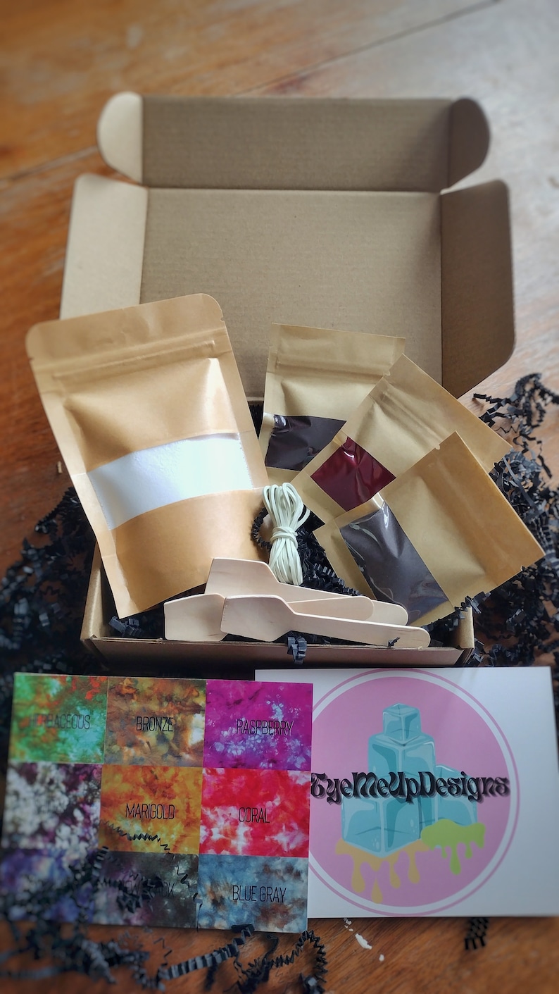 May include: A craft kit with various colored dye packets, wooden spoons, and a card with color swatches. The kit includes a box, several small bags of dye, and a card with the text "EyeMeUpDesigns".