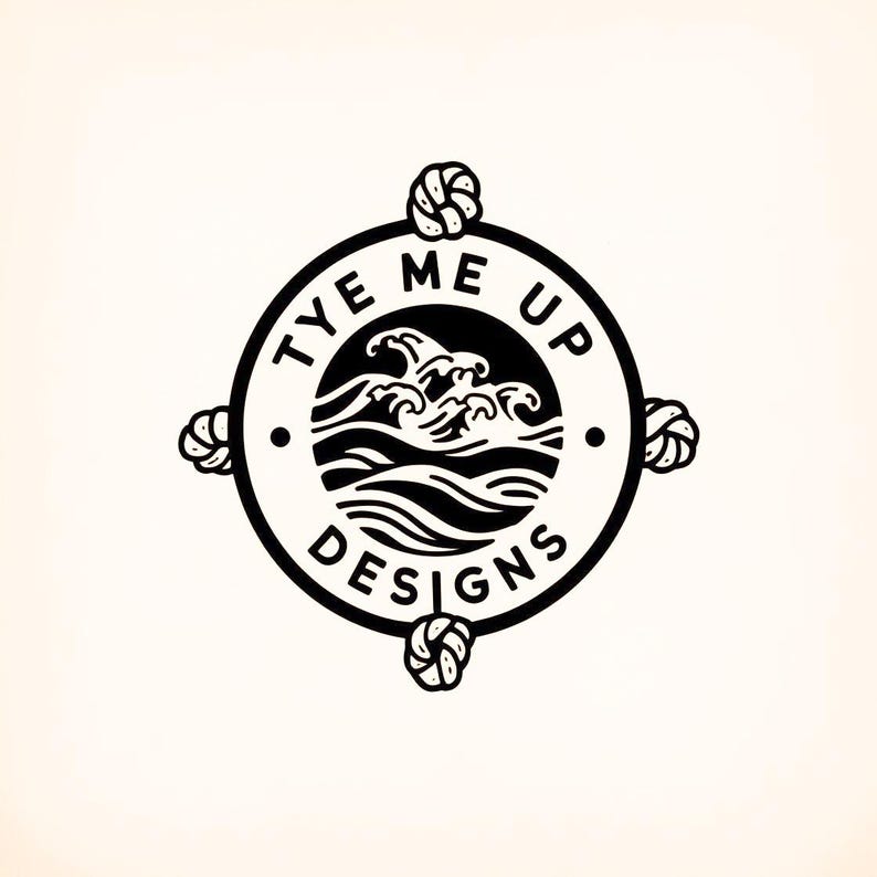 Op de afbeelding: Zwart-wit logo met de tekst "TYE ME UP DESIGNS" in een cirkelvormig ontwerp. Het logo bevat een golfafbeelding in het midden en nautische knopen op de kardinale punten. Het ontwerp staat tegen een cr&egrave;mekleurige achtergrond.
