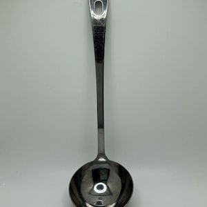 May include: A polished stainless steel soup ladle featuring a long, slender handle with a rounded end and a circular hanging hole. The bowl of the ladle is deep and hemispherical, designed for serving liquids with a smooth, reflective metallic finish.