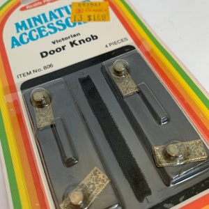 May include: A package of four Victorian door knobs for miniature dollhouses. The knobs are gold-colored and have a detailed design. The package is labeled "Miniature Accessories" and "Victorian Door Knob".