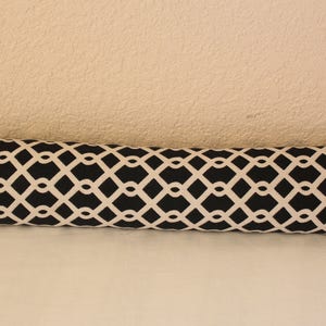 May include: A black and white patterned bolster pillow with a geometric design.