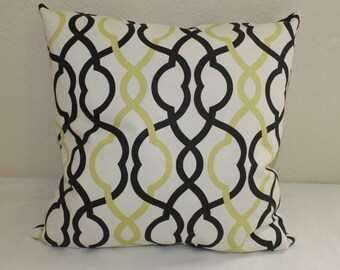 May include: A white throw pillow with a black and yellow geometric pattern. The pattern is a repeating design of interlocking loops and curves.