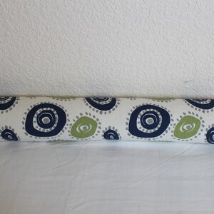 May include: A white, green, and blue patterned bolster pillow. The pillow is cylindrical and has a repeating pattern of circles with a white background.