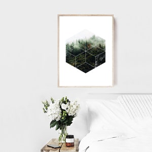 May include: A framed print with a forest scene in a geometric cube design. The artwork depicts a green forest with a misty atmosphere. The frame is light wood, and the overall aesthetic is modern and natural. The print is in a bedroom setting.
