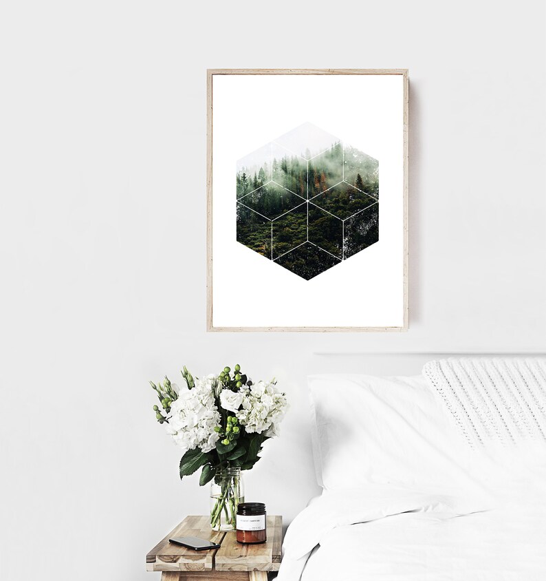 May include: A framed print with a forest scene in a geometric cube design. The artwork depicts a green forest with a misty atmosphere. The frame is light wood, and the overall aesthetic is modern and natural. The print is in a bedroom setting.