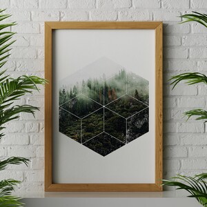 May include: A framed art print depicting a forest scene within a geometric design. The artwork is set against a white background and framed in a light brown wooden frame. Green plants frame the artwork.
