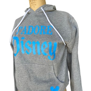 May include: A gray hooded sweatshirt with a blue "J'adore Disney" graphic and a blue Mickey Mouse silhouette on the pocket.