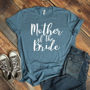 a t - shirt that says mother of the bride next to a pair of jeans