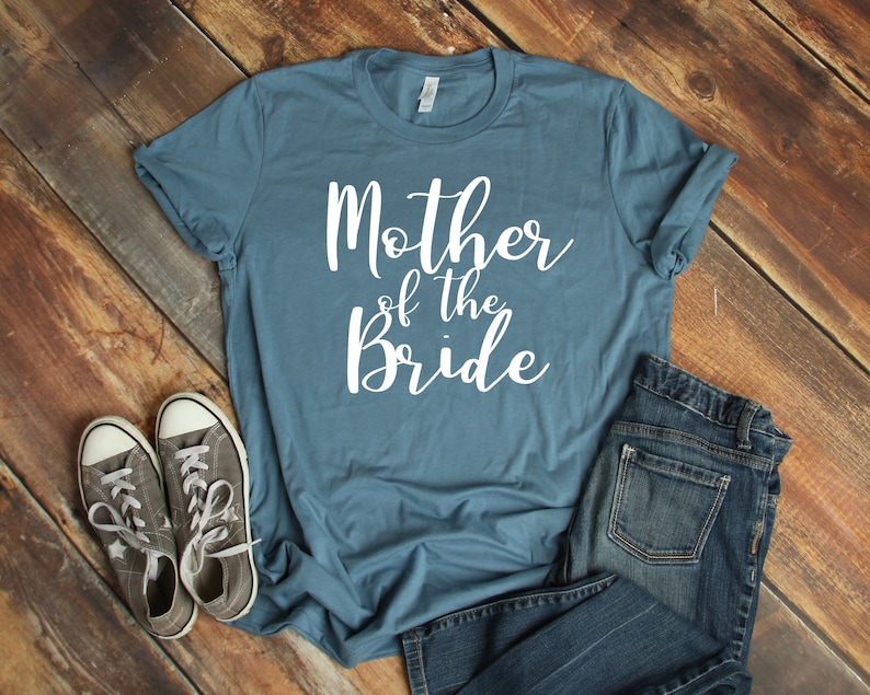 a t - shirt that says mother of the bride next to a pair of jeans