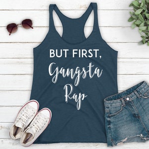May include: A dark blue tank top with the text "BUT FIRST, Gangsta Rap" in white lettering.