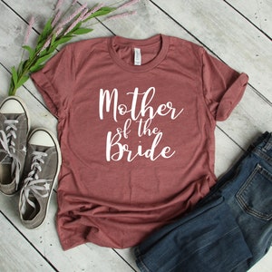 a t - shirt that says mother of the bride next to a pair of jeans