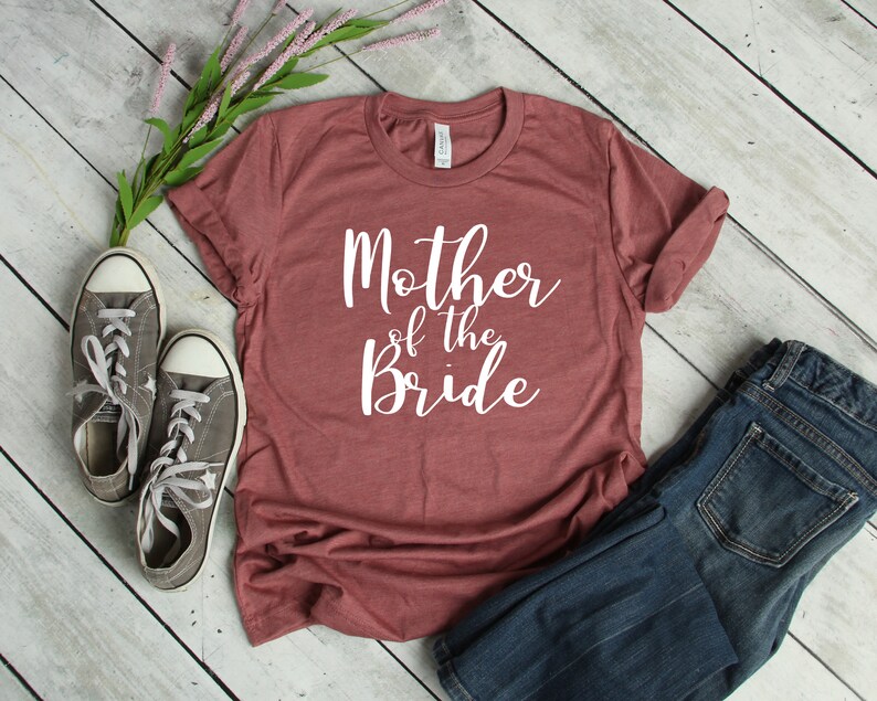 a t - shirt that says mother of the bride next to a pair of jeans