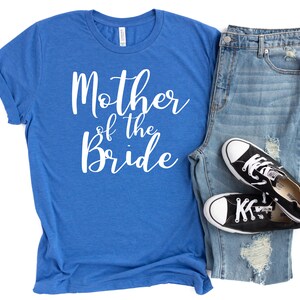 a t - shirt that says mother of the bride next to a pair of jeans