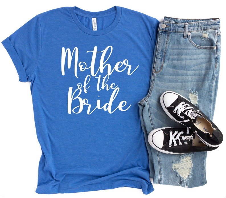 a t - shirt that says mother of the bride next to a pair of jeans