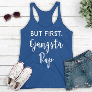 May include: A blue tank top with the text "BUT FIRST, Gangsta Rap" in white lettering.