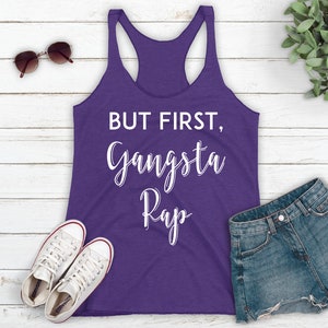 May include: Purple tank top with white text that reads "But first, Gangsta Rap".
