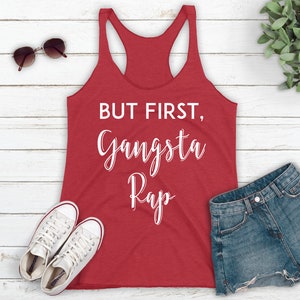 May include: Red tank top with white text that reads "But first, Gangsta Rap".