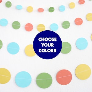 May include: A garland of paper circles in yellow, green, blue, and orange. The garland is strung on white thread. The text "Choose Your Colors" is written in white on a blue circle.