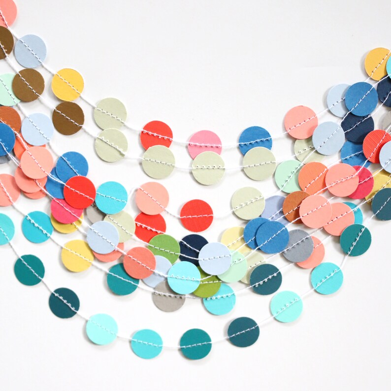 May include: A colorful garland featuring multiple strands of paper circles in various colors, including red, blue, yellow, and green. The circles are strung together with white thread, creating a festive and decorative element.