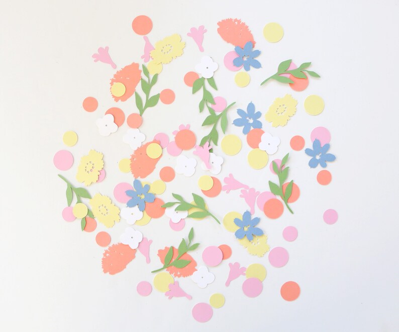 Puede incluir: Una colecci&oacute;n de recortes de papel coloridos, que incluyen flores, hojas y c&iacute;rculos. Las flores son de color amarillo, azul y blanco, con hojas verdes y c&iacute;rculos rosas, naranjas y amarillos. Los recortes est&aacute;n esparcidos sobre un fondo blanco.