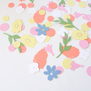 Puede incluir: Una colecci&oacute;n de recortes de papel coloridos esparcidos sobre una superficie blanca. Los recortes incluyen flores amarillas, rosas y azules, hojas verdes y varias formas en tonos naranja, rosa y amarillo. El tema general es floral y decorativo.