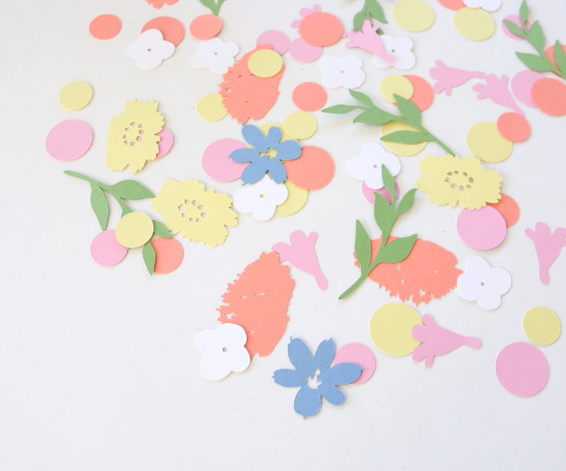 Puede incluir: Una colecci&oacute;n de recortes de papel coloridos esparcidos sobre una superficie blanca. Los recortes incluyen flores amarillas, rosas y azules, hojas verdes y varias formas en tonos naranja, rosa y amarillo. El tema general es floral y decorativo.