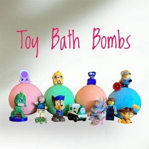 May include: Toy bath bombs with various cartoon characters on top, including Paw Patrol, a Minion, and a Ninja Turtle. The bath bombs are in different colours, including pink, green, blue, and orange.