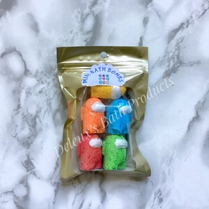 May include: A clear plastic bag with a gold zipper closure contains five colourful bath bombs shaped like the characters from the video game Among Us. The bag has a white label that says "Mini Bath Bombs".
