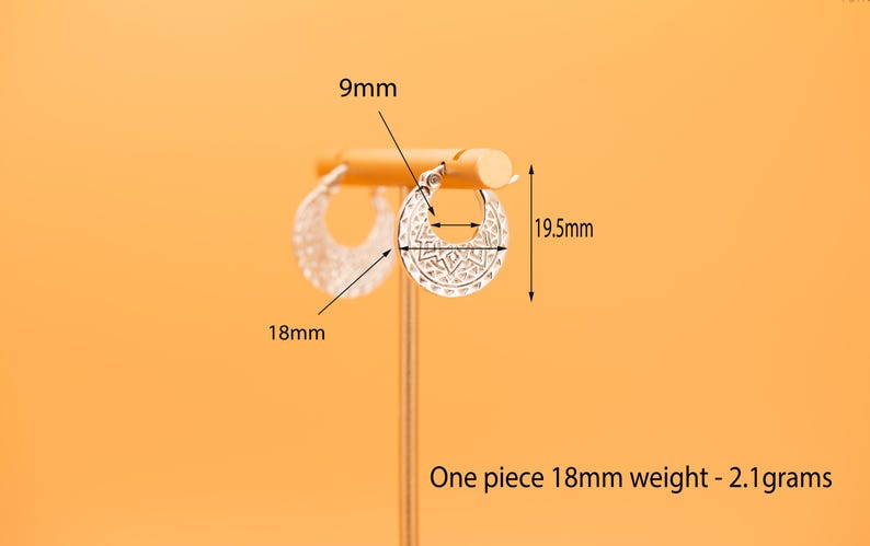 Peut inclure: Une paire de cr&eacute;oles argent&eacute;es avec un motif g&eacute;om&eacute;trique d&eacute;coup&eacute;. Les boucles d'oreilles mesurent 18 mm de largeur, 19,5 mm de hauteur, avec un diam&egrave;tre int&eacute;rieur de 9 mm. Chaque boucle p&egrave;se 2,1 grammes, comme indiqu&eacute; par le texte.